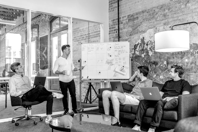 Sales trainees gathered around a whiteboard during a team training session