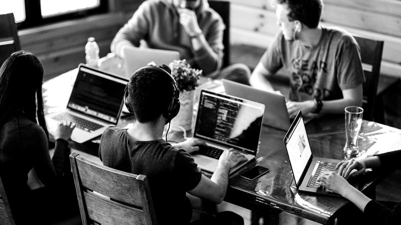 Team of sales professionals working on laptops at a shared table